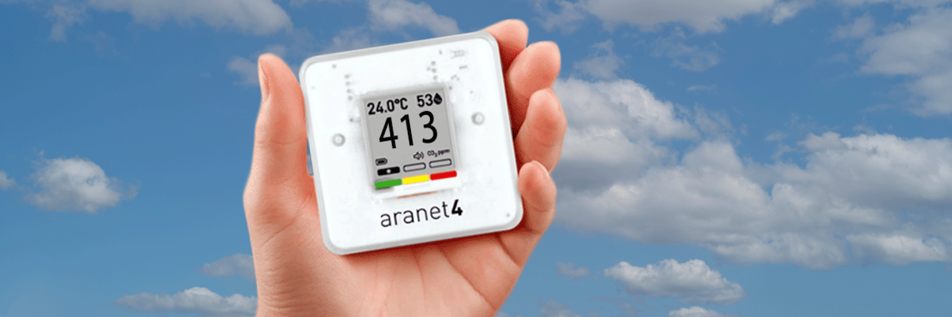 Hand holding a Co2 Monitor with cloudy sky