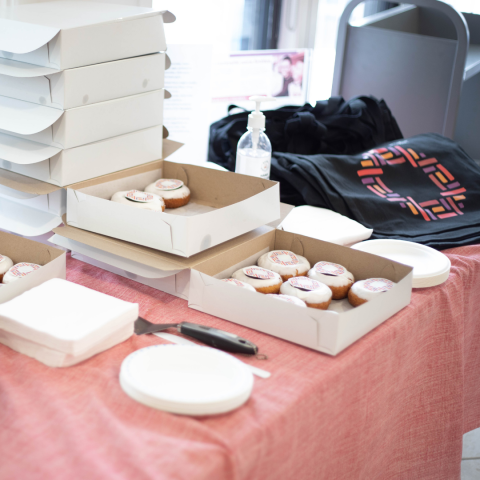Tabled filled with boxes of branded donuts and beside these, tote bags